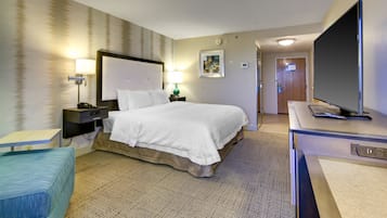 A hotel room with a bed, bedside tables with lamps, a television, and a small seating area.