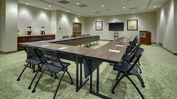 A conference room with a long table, chairs, a coffee station, and artwork on the walls.