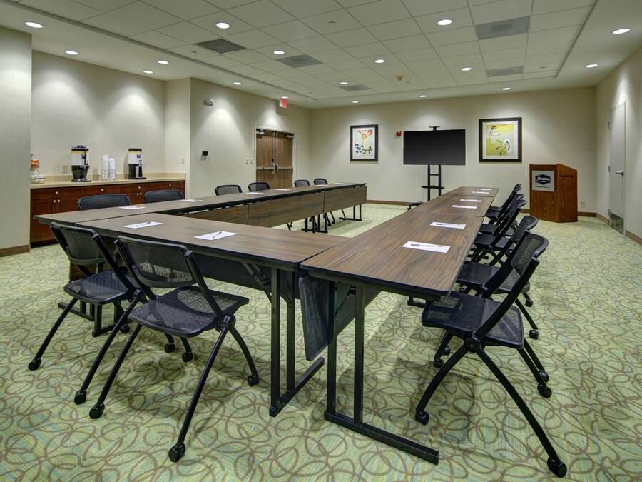 A conference room with a long table, chairs, a coffee station, and artwork on the walls.