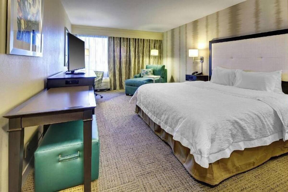 Een hotelkamer met een bed, bureau, stoel en een televisie.