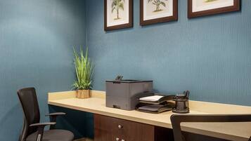 A conference room with a desk, chairs, a printer, and framed botanical prints on the wall.