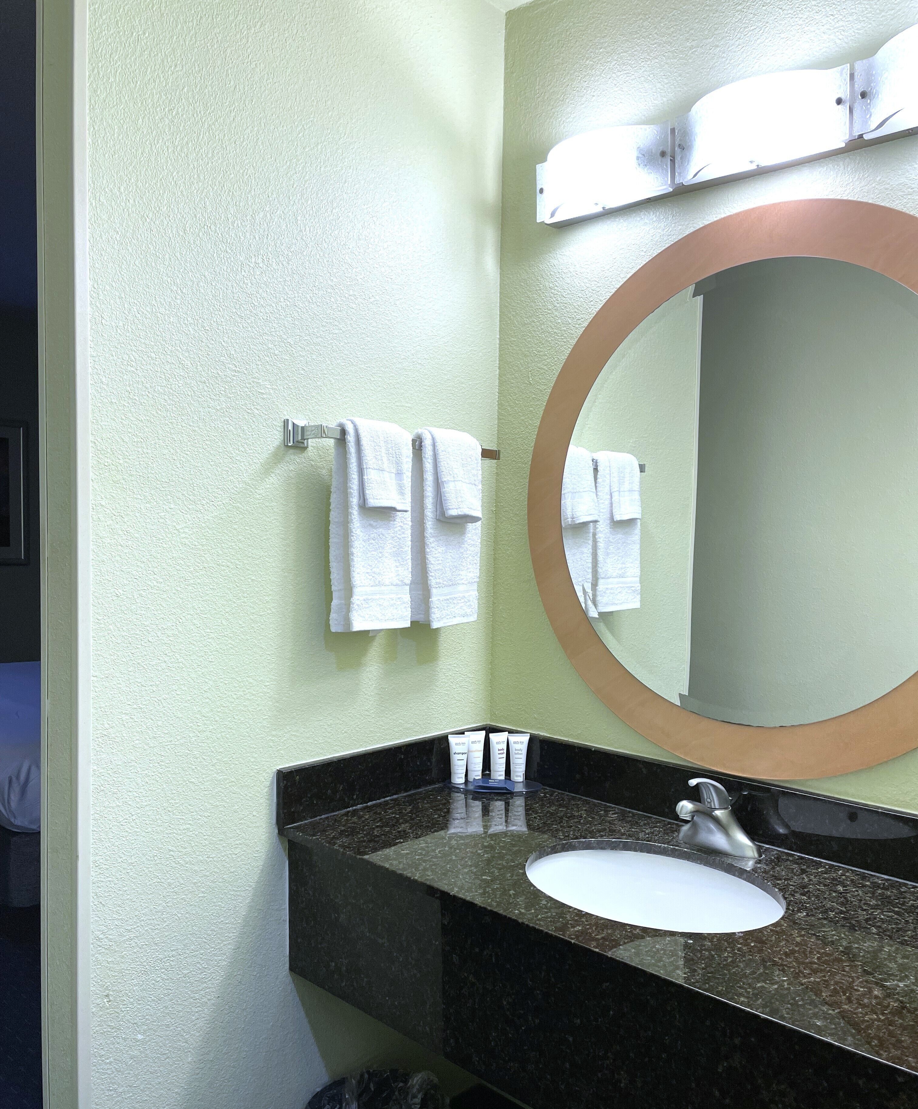 A bathroom with a sink, mirror, and towels on a rack.