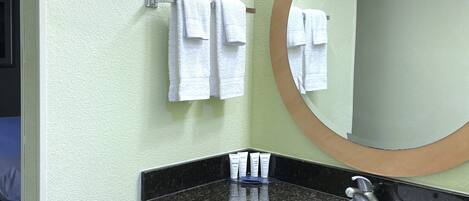 A bathroom with a sink, mirror, and towels on a rack.