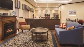 Een hotel lobby met een open haard, een bank, een ronde tafel, een bar en een televisie.