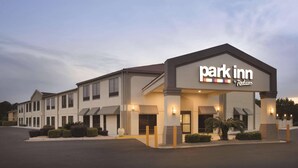 Een Park Inn by Radisson hotel met een moderne gevel, meerdere ingangen en een goed verlichte buitenkant.