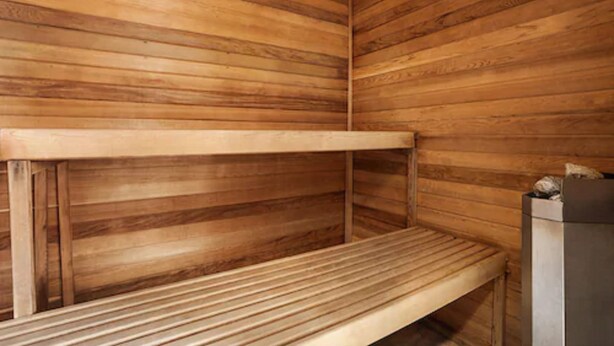 Een houten sauna met banken en een metalen bak.