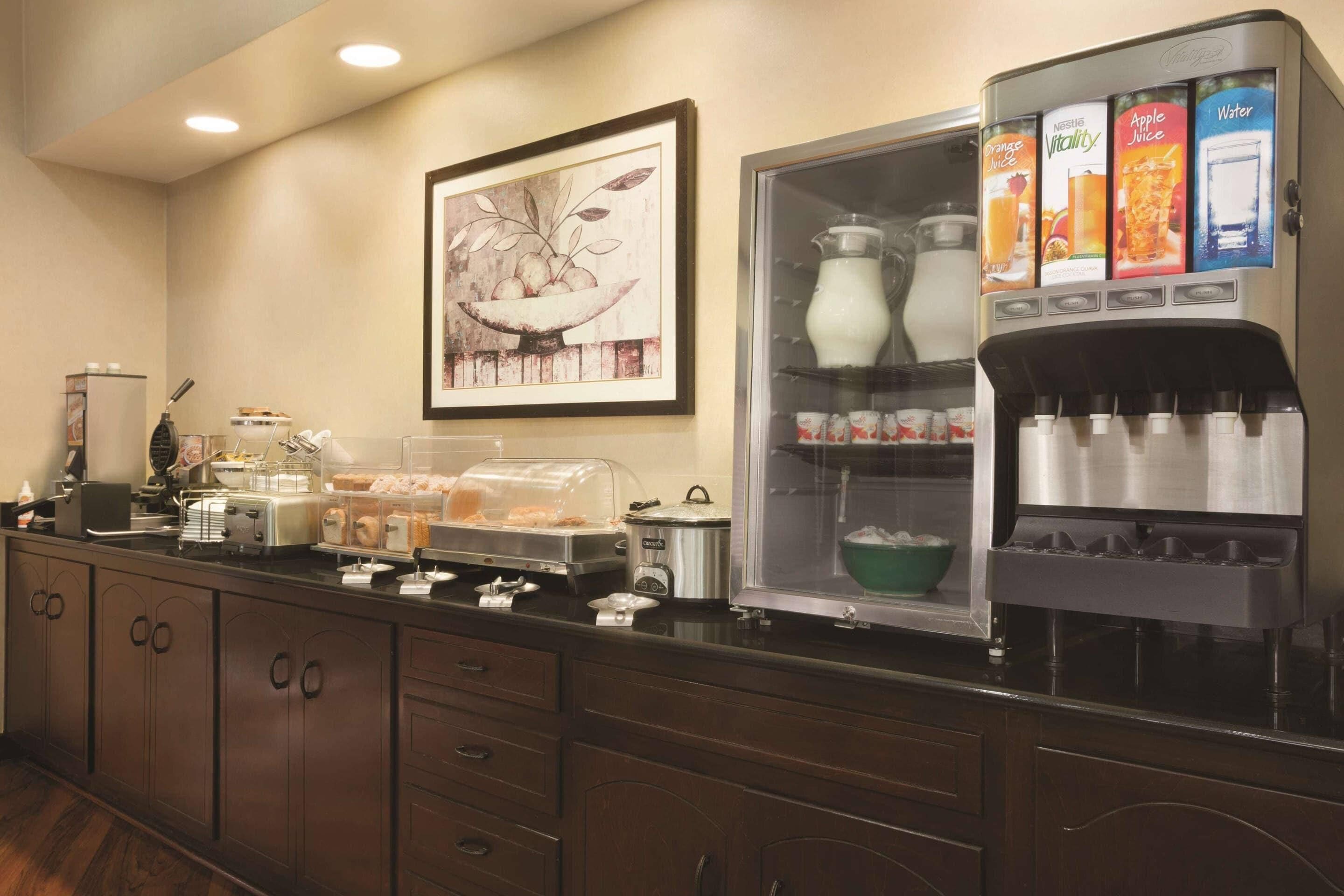 A breakfast bar with a coffee maker, toaster, and food display.