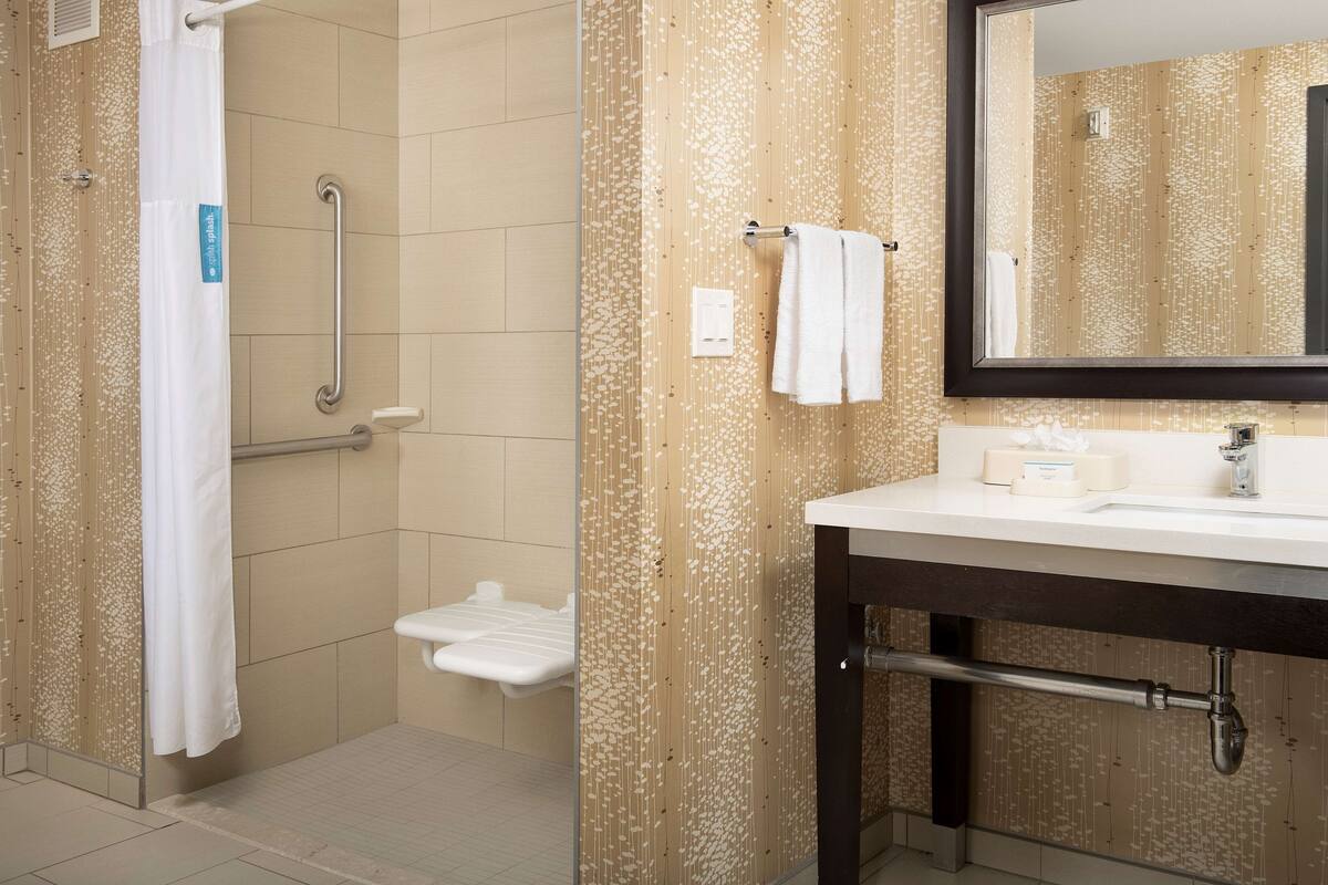 A bathroom with a shower, a toilet, a sink, and a mirror.