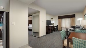 A hotel room with a kitchenette, a dining area with a table and chairs, a TV, and a bed. - Hampton Inn & Suites Alpharetta (Alpharetta)