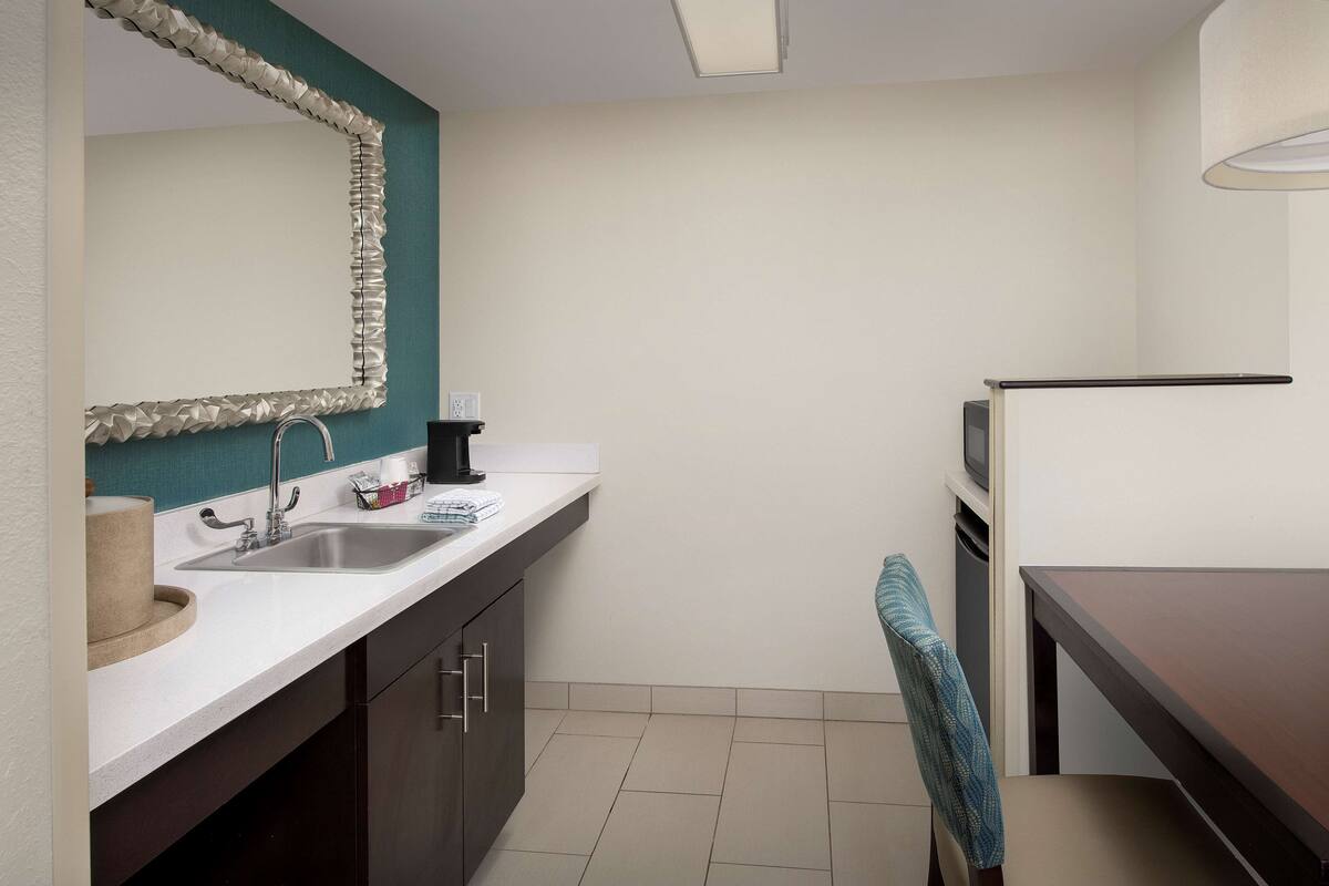 A compact kitchen with a sink, countertop, and a microwave.