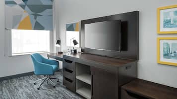 Un espacio de oficina moderno con un escritorio, una silla y un televisor de pantalla plana grande.