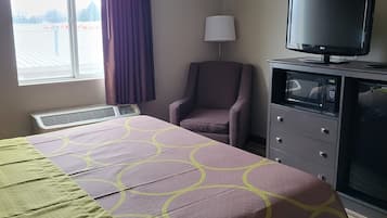 A hotel room with a bed, a television, a chair, a desk, and a window.