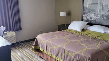 Habitación de hotel con cama, escritorio, lámpara y vista a la ciudad.