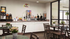 A breakfast area with a counter, coffee machines, and seating. - Super 8 by Wyndham Aurora/Naperville Area (Aurora)