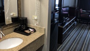 A hotel bathroom with a granite countertop sink, a mirror, a hair dryer, and a coffee maker. - Super 8 by Wyndham Aurora/Naperville Area (Aurora)