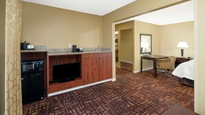 Une chambre d’hôtel équipée d’une kitchenette, d’un lit, d’un bureau et d’une chaise.