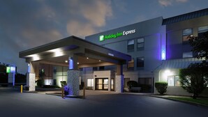 A Holiday Inn Express hotel with a covered entrance, outdoor seating, and a well-lit facade.