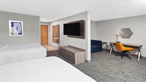 A hotel room with a bed, a desk, a chair, a TV, and a wardrobe.