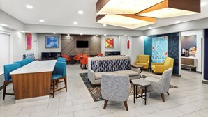 A modern hotel lobby with a long dining table, sofas, and chairs.