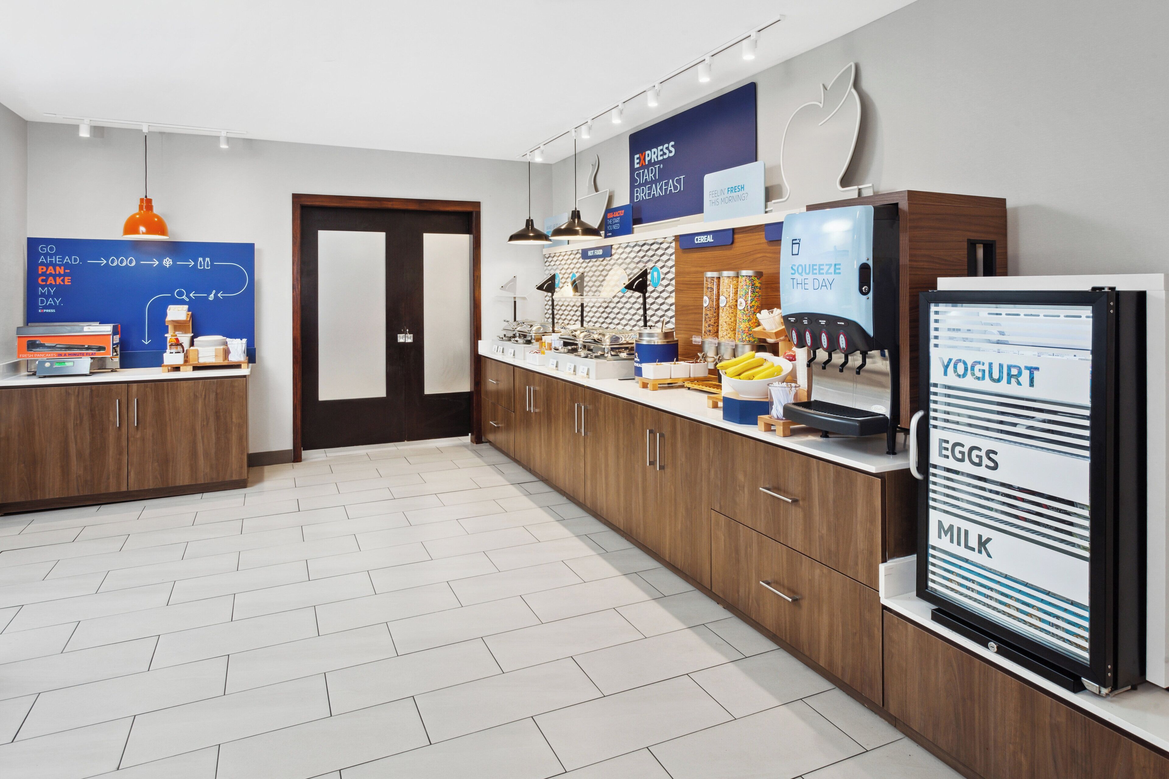 A modern kitchen with a breakfast bar, a refrigerator with yogurt, eggs, and milk, and a coffee machine.