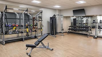 Un gimnasio con diferentes equipos de ejercicio, como bancos, estantes para pesas y mancuernas.