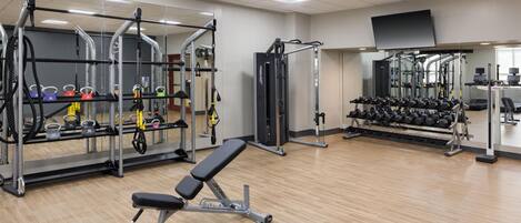 A gym with various exercise equipment, including a bench, weight racks, and dumbbells.
