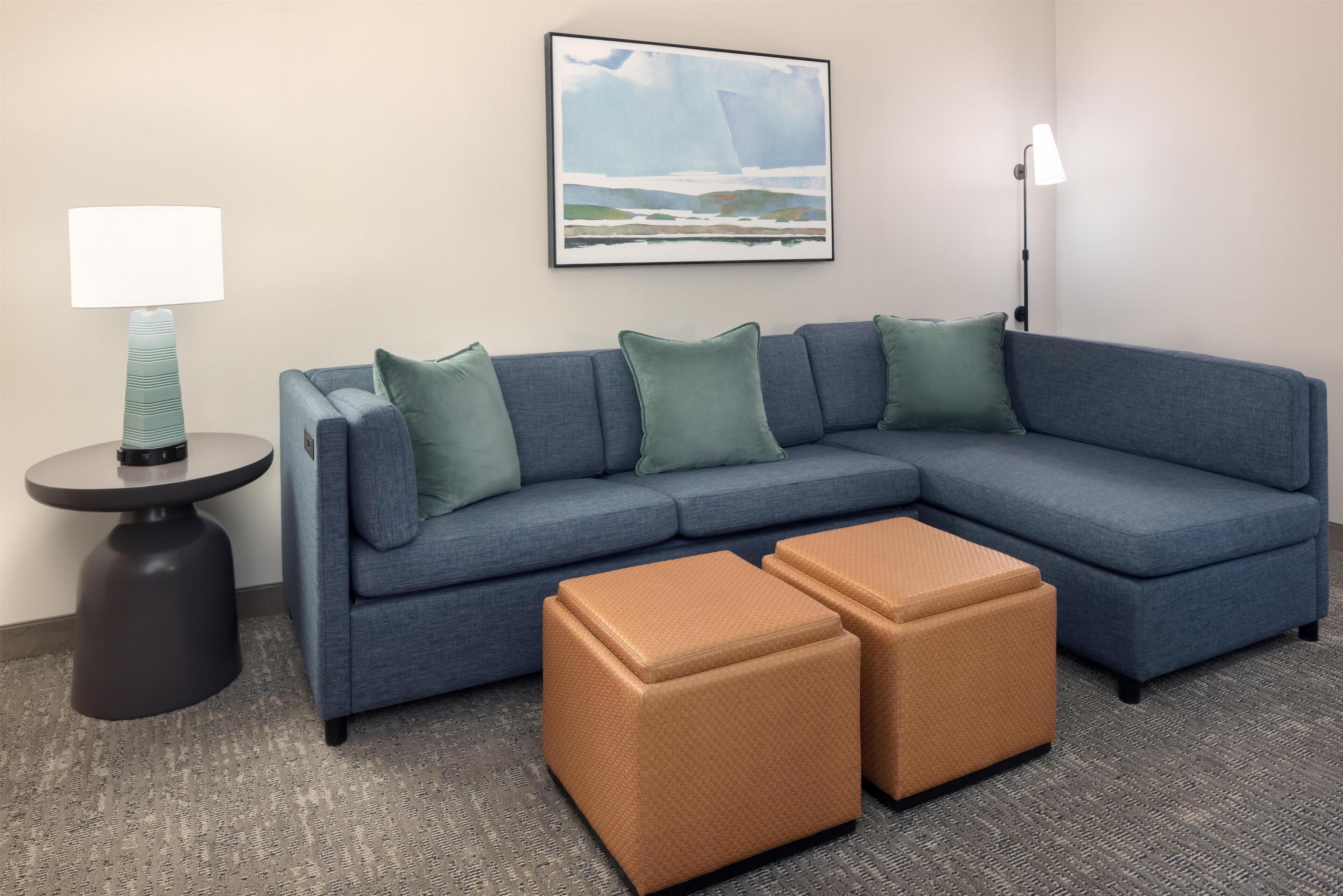 A sectional sofa with matching cushions, a round side table, a floor lamp, and two ottomans.