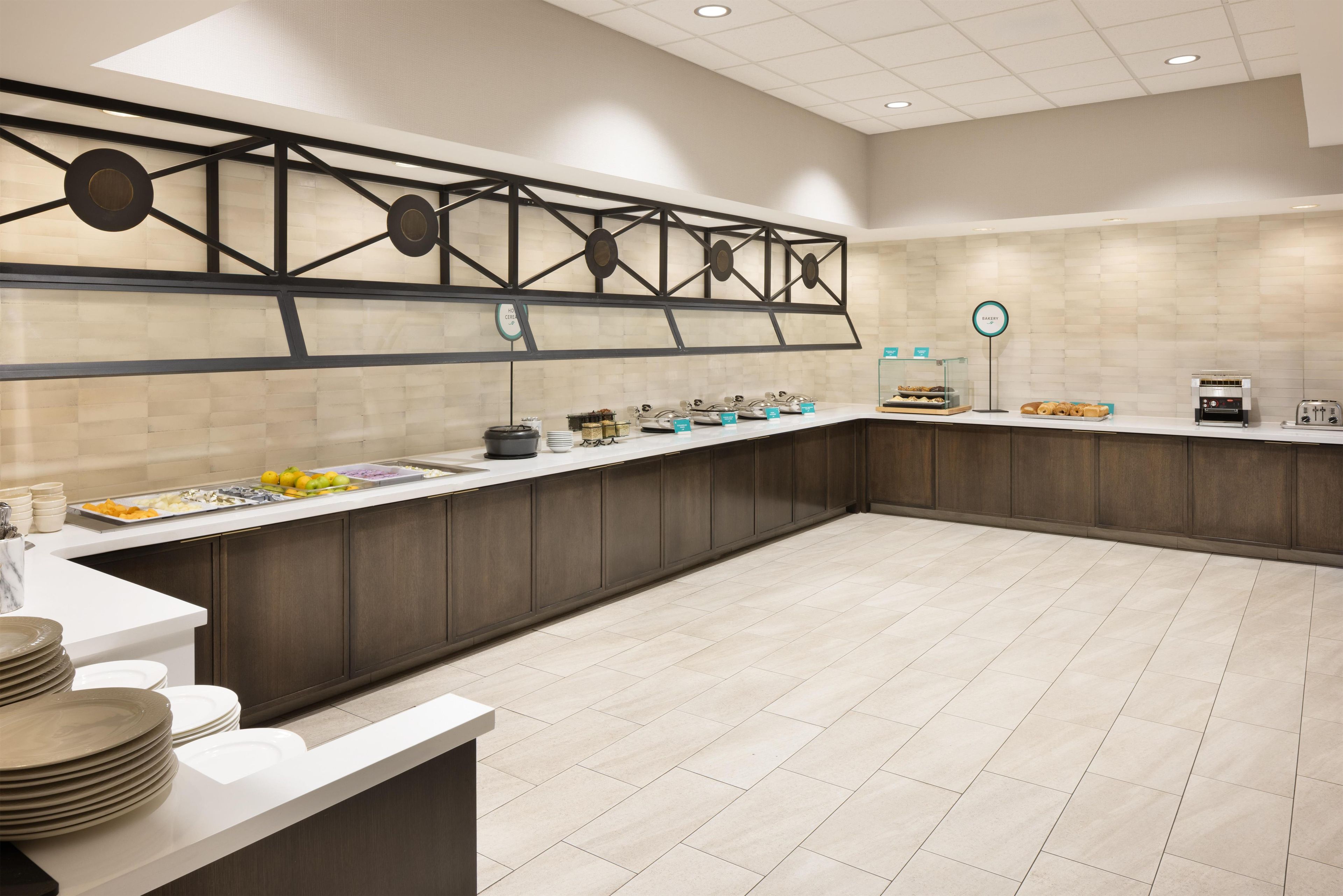A modern kitchen with a breakfast bar, a coffee station, and a bakery sign.