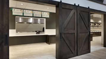 Cozinha moderna com porta corrediça estilo rústico, coifa de aço inoxidável e lousa de cardápio sobre o balcão.