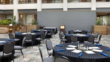 Une salle de conférence d’hôtel équipée de plusieurs tables et chaises, d’un pupitre et d’un escalier menant à un niveau supérieur.