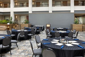 A hotel conference room with multiple tables and chairs, a podium, and a staircase leading to an upper level. - Embassy Suites by Hilton Lexington/UK Coldstream (Lexington)
