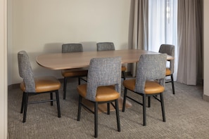 Un salón de conferencias con una mesa de madera y seis sillas tapizadas con asientos de cuero.