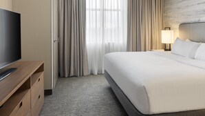 A hotel room with a bed, a TV, a desk, and a lamp. - Embassy Suites by Hilton Lexington/UK Coldstream (Lexington)
