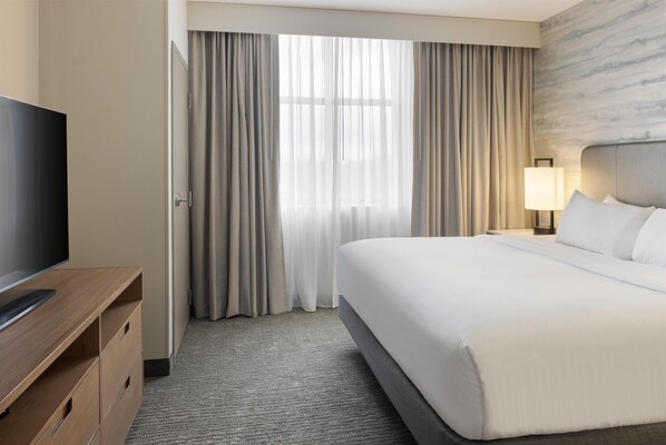 A hotel room with a bed, a TV, a desk, and a lamp. - Embassy Suites by Hilton Lexington/UK Coldstream (Lexington)