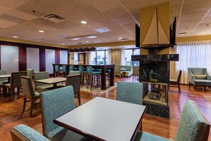 A hotel lobby with a seating area, a fireplace, and a television mounted on the wall.