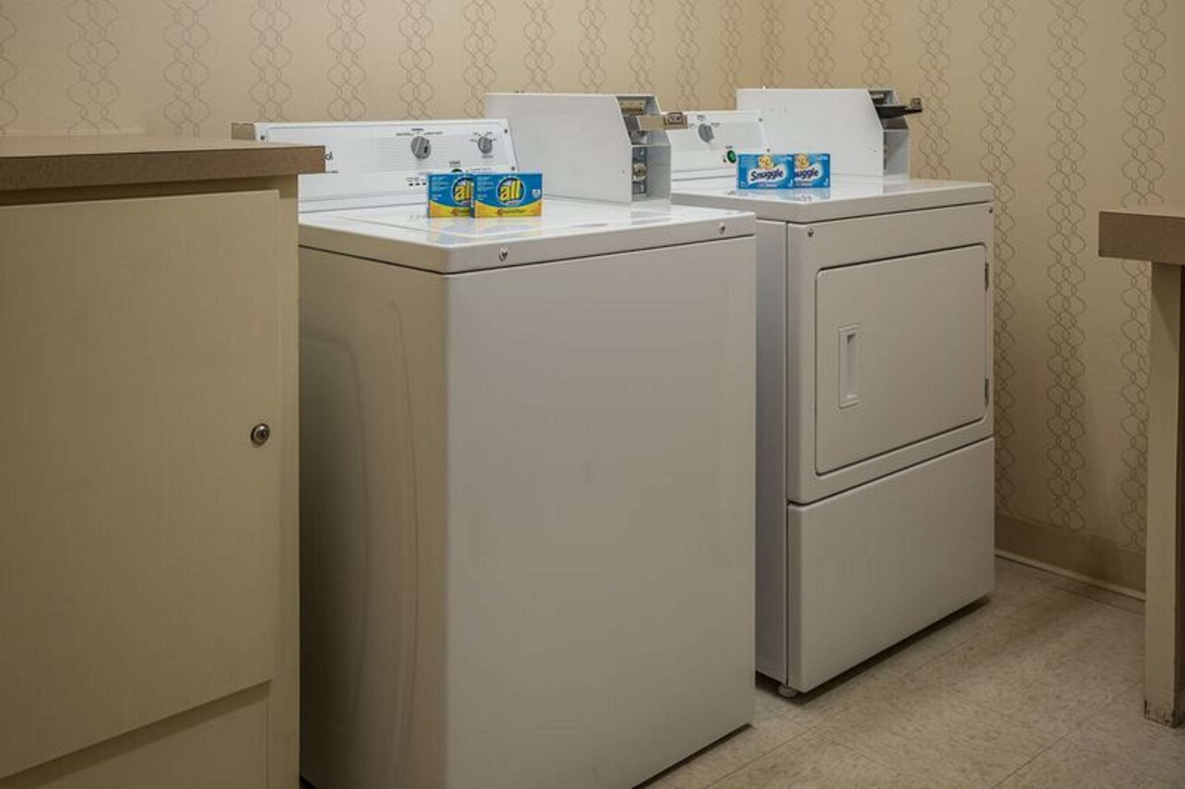 A laundry area with two front-loading washing machines and a cabinet.