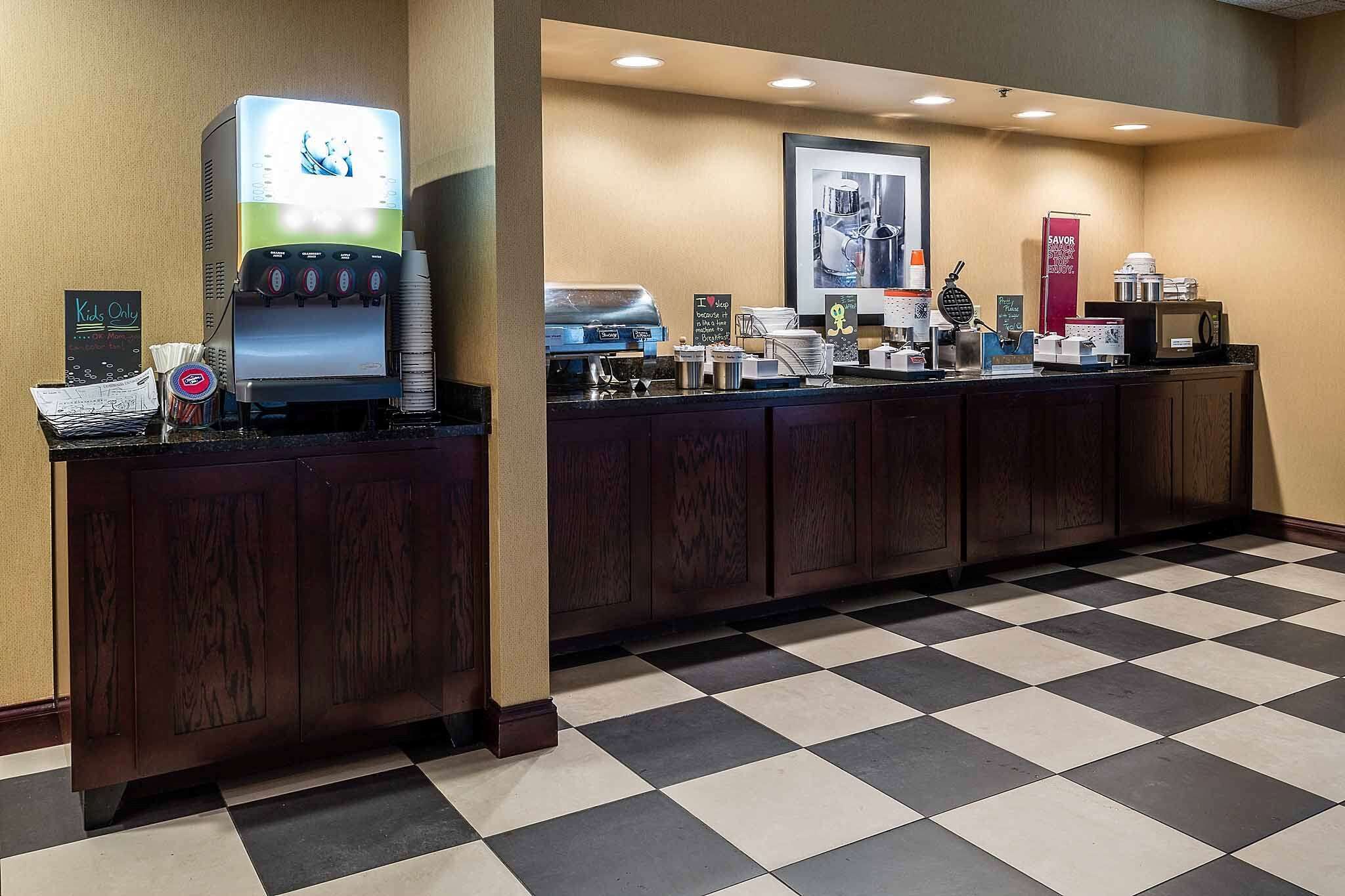 A hotel reception area with a coffee machine, a "Kids Only" sign, and a check-in counter.