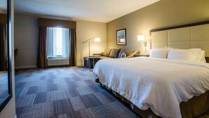 A hotel room with a large bed, a bedside table, a lamp, and a window with curtains. - Hampton Inn Somerset (Somerset)