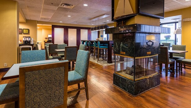 A hotel lobby with wooden flooring, seating areas, a fireplace, and a television mounted on the wall. - Hampton Inn Somerset (Somerset)