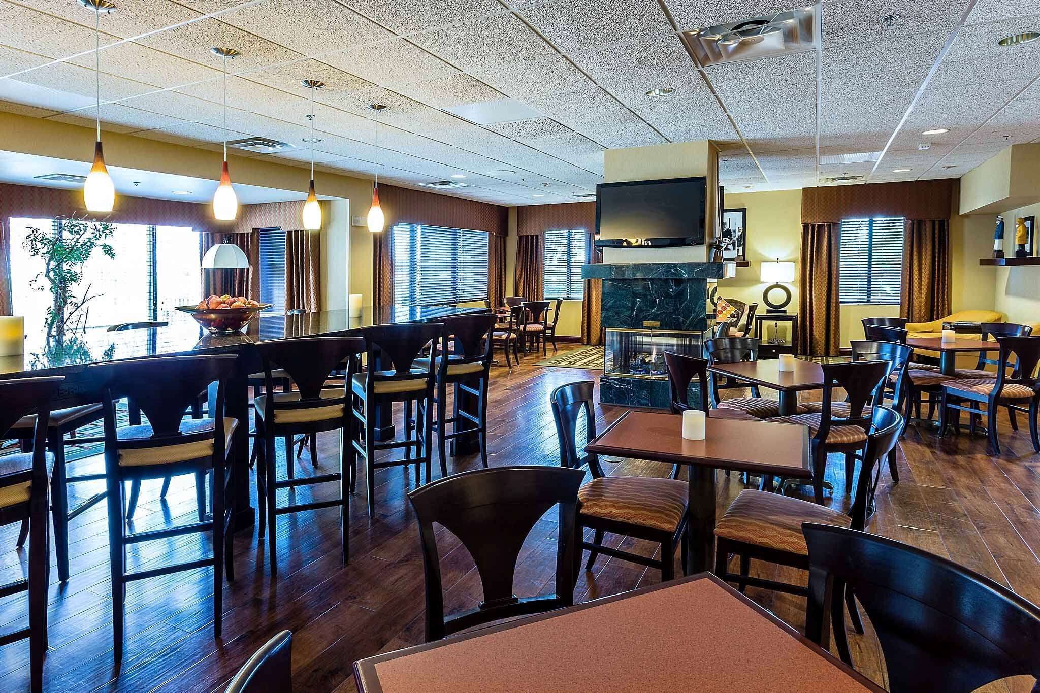 A spacious restaurant with multiple tables and chairs, a fireplace, and pendant lighting.