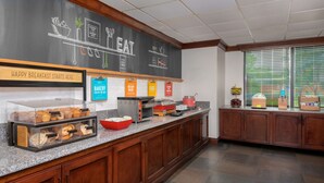 A breakfast bar with various food items and a chalkboard menu.