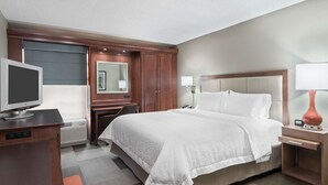 A hotel room with a large bed, a desk with a flat-screen TV, a desk lamp, and a bedside table with a lamp. - Hampton Inn Boston/Marlborough (Marlborough)