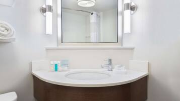 A modern bathroom with a white sink, a mirror, and a shower curtain.