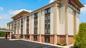 A Hampton Inn hotel with a modern facade, a covered entrance, and a parking lot.