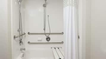 A modern bathroom with a bathtub, shower, and grab bars.