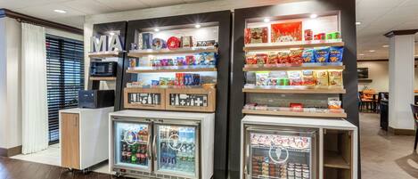 Un área de venta con microondas, refrigeradores y estantes de aperitivos.