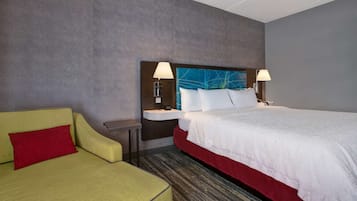 Een hotelkamer met een bed, een slaapbank, een nachtkastje en een lamp.