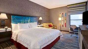 A hotel room with a large bed, a desk, a chair, a TV, and a window with a view.
