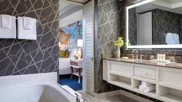 A modern bathroom with a large bathtub, a vanity with a mirror, and a patterned wall.
