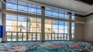 A spacious lobby with large windows, a colorful carpet, and a view of Mandalay Bay.